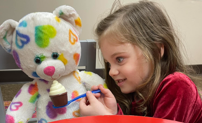 Child feeding teddy bear