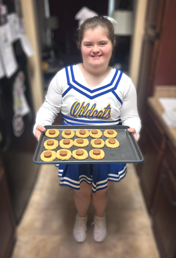 Girl in cheerleading uniform with cookie tray